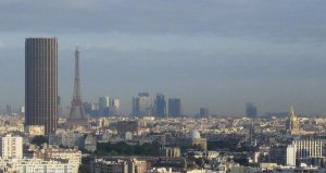 Panoramic view of Paris skyline showing Montparnasse Tower on the left, Eiffel Tower center, and La Défense district in the distance
