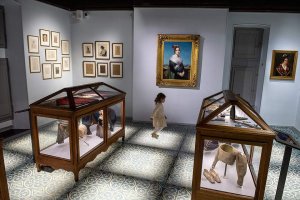young visitor in museon arlaten 19th century costume room with portrait of arlesienne in background