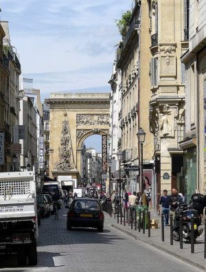Street view of Rue Saint-Denis with historic stone archway in Paris