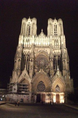Nighttime view of the west facade of Reims Cathedral illuminated