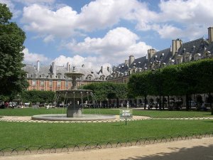 Central square Place des Vosges in Paris with old brick buildings and paved courtyard under clear sky