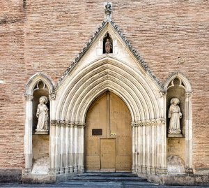 Gothic-style portal entrance of Notre-Dame du Taur church with statues in niches