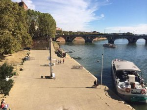 View of the Garonne River along the Quai de la Daurade in Toulouse with riverside buildings