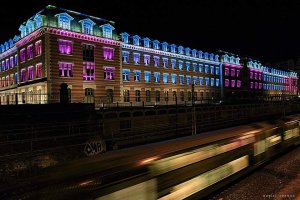 Nighttime view of Manufacture des Tabacs college lit up with a train passing in Lyon