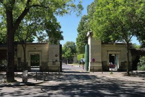 Entrance gate of Montparnasse Cemetery with surrounding trees and pathway
