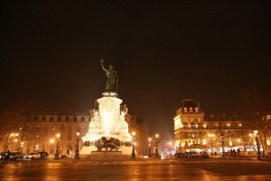 Nighttime view of Place de la République illuminated with streetlights and surrounding buildings in Paris