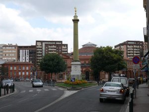 Tall Colonne Dupuy monument in a city square with clear sky