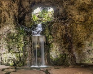 artificial waterfall surrounded by rocky grotto in Parc des Buttes-Chaumont