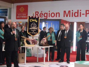 Group of men speaking and posing during Noir de Bigorre confraternity event at Toulouse exhibition center