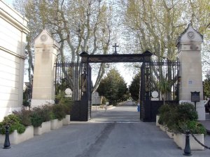 Main northern entrance of Saint Pierre Cemetery with historic stone gate and surrounding urban area