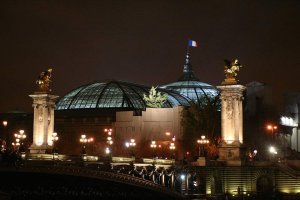 nighttime view of bridge and illuminated Grand Palais in Paris
