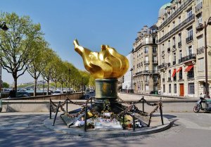 Golden flame-shaped torch sculpture with a clear sky background