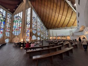 Interior view of the Church of St Joan of Arc featuring stained glass and wooden pews