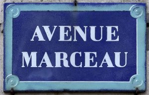 Street name sign for Avenue Marceau in Paris mounted on a beige wall