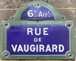 Blue and white street name sign for rue de Vaugirard mounted on a building wall