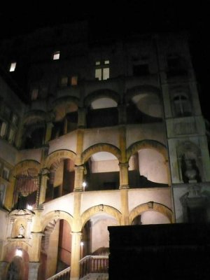 Partial view of Maison Henri IV building at night with historic bust in courtyard