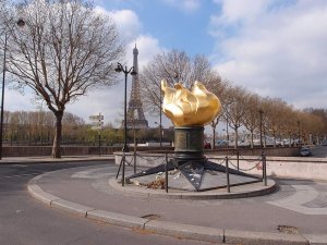 golden Flame of Liberty monument surrounded by trees in Paris