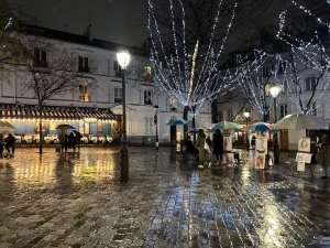 nighttime view of Place du Tertre in Paris with illuminated square and surrounding buildings
