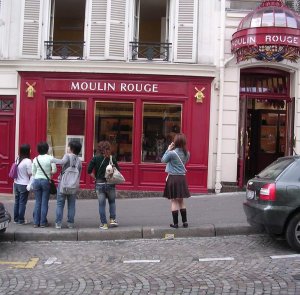 Group of Asian tourists standing outside the secondary entrance of the Moulin Rouge
