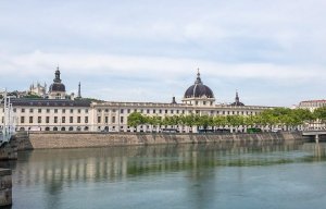 Historic Hôtel-Dieu de Lyon building by the Rhône river under a clear sky